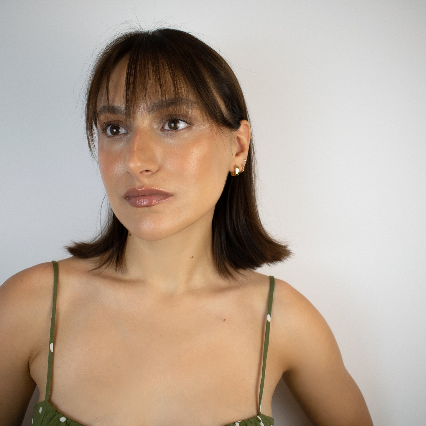 Cercei argint placat cu aur 18K cu design patratos la urechea unei femei Callie on a woman wearing a gold vermeil square design hoop earrings