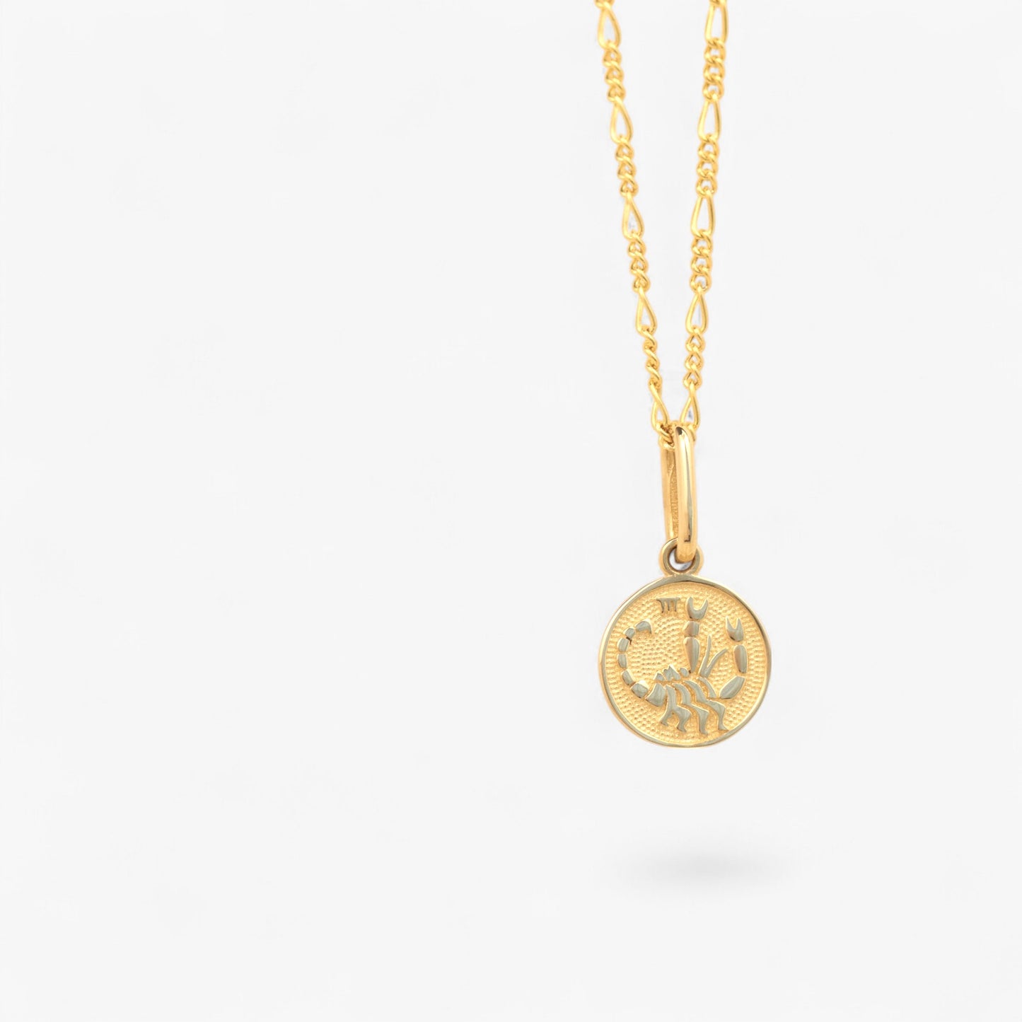 Pandantiv cu zodia scorpion din aur de 14k pe lant din aur de 14k pe fundal alb. 14k solid gold Scorpio zodiac charm on a 14k solid gold necklace on a white background