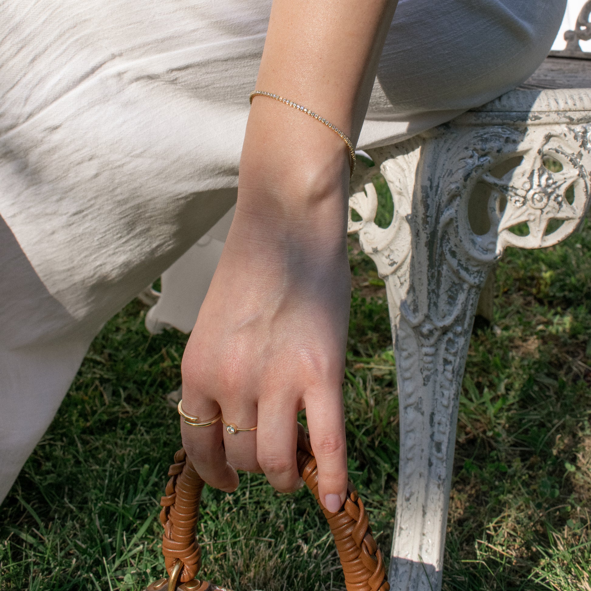 A close-up lifestyle shot of a person's hand wearing a tennis sterling silver gold plated bracelet.
