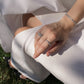 A close-up of a person's hand resting on their lap, wearing two silver rings and a matching silver bracelet with emerlad cut zirconia stones.